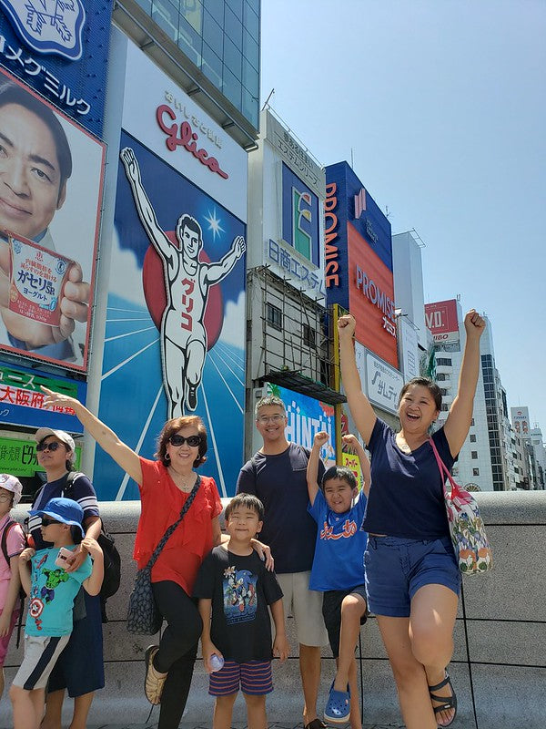 Joanne Kwong and her family in front of the Glico running man billboard in Osaka
