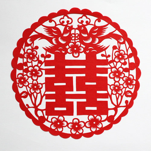 Red Chinese paper cut of double happiness symbol surrounded by flowers and with two love birds