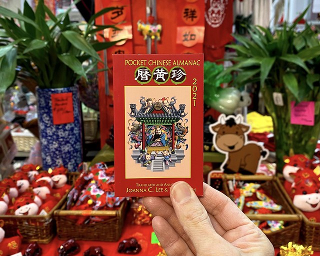 Chinese pocket almanac held in front of Lunar New Year display