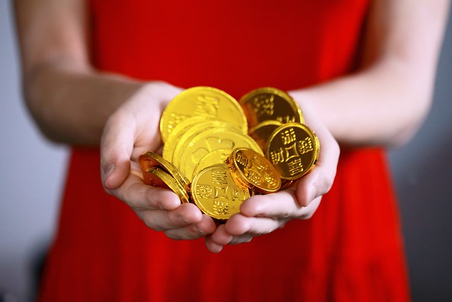 Woman in red dress holding gold chocolate coins