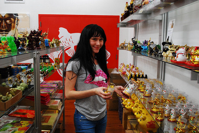 College student Skye in Pearl River Mart, browsing lucky cat figurines
