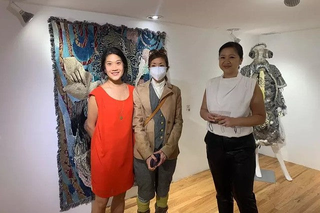 Artists Joyce Yu-Jean Lee and aricoco with Pearl River Mart President Joanne Kwong in the Pear River Mart gallery in front of large tapestry artwork