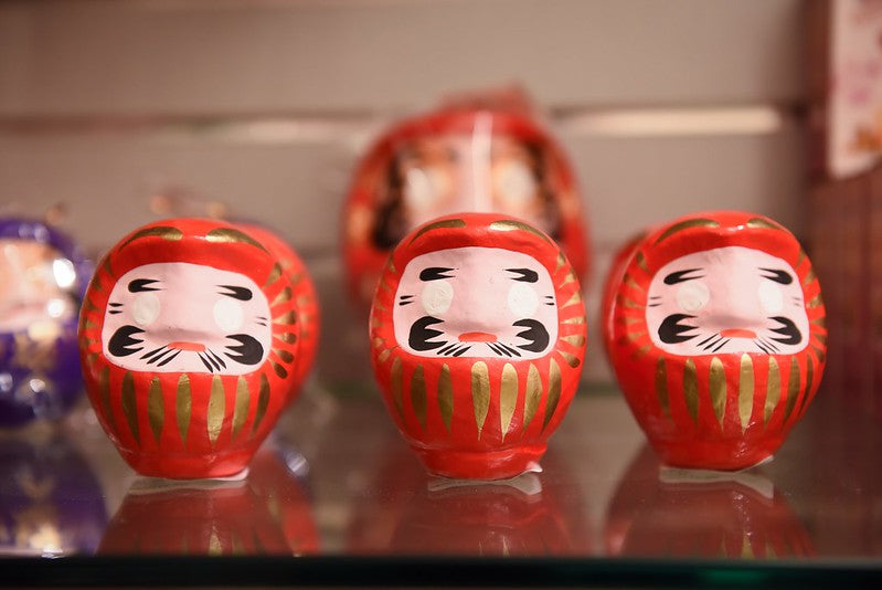 Three red daruma dolls on a shelf