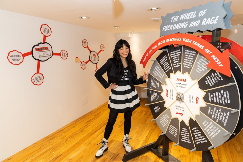 Artist Risa Puno with her gaming wheel and wall decals in a gallery 