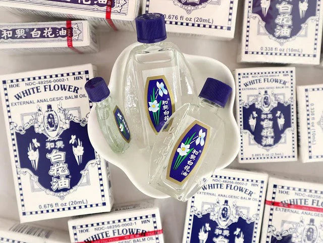 Bottles of White Flower Oil in dish surrounded by boxes of White Flower OIl