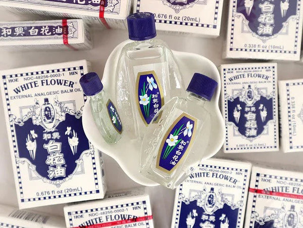 Bottles of White Flower Oil in dish surrounded by boxes of White Flower OIl