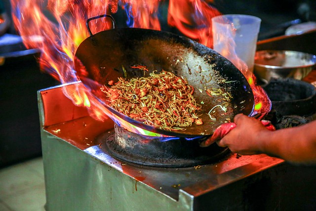 Wok being used with fire to cook vegetables