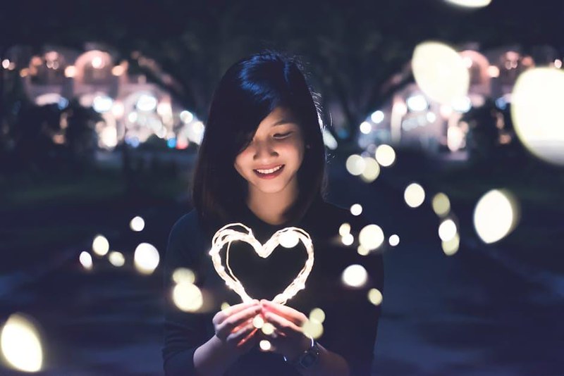 Woman holding heart-shaped light
