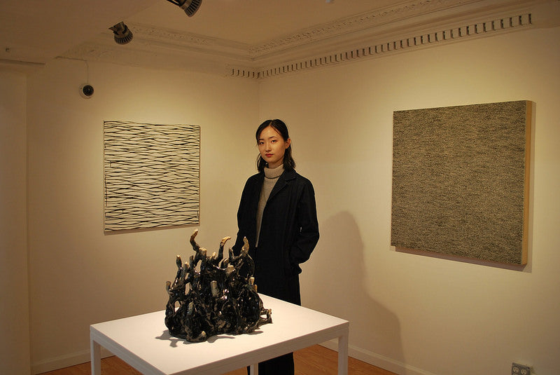 Artist Yingqian Cao with sculpture and abstract paintings in Pearl River Mart art gallery in Tribeca
