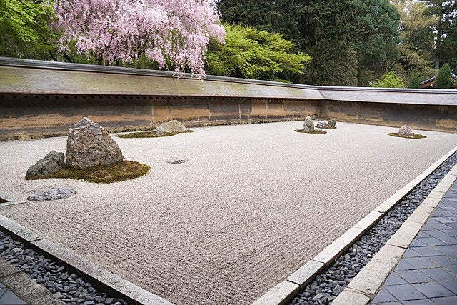 Japanese zen garden with manicured gravel, stones, and cherry blossom tree