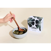 Person stirring bowl of seaweed soup beside box of OMA seaweed soup