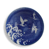 A round blue and white ceramic plate featuring a traditional Japanese-style design with white cranes flying over white waves on a deep cobalt blue background.