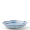 A shallow round ceramic plate with a blue and white striped ribbed pattern, photographed against a solid white background.
