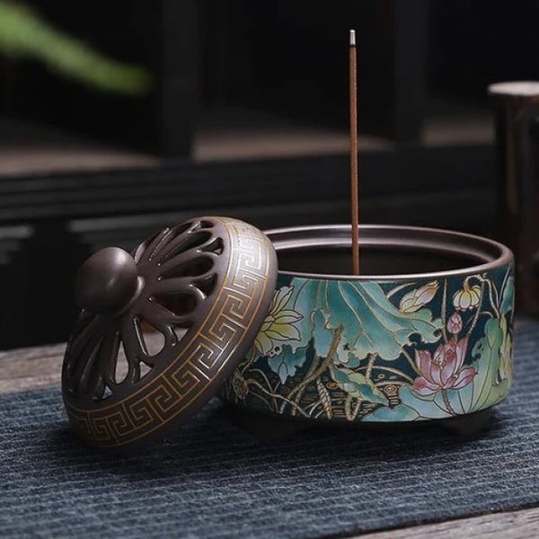 Round Enamel Incense Burner with Lotus design. The lid of the burner is taken off and a sample incense is standing upright.