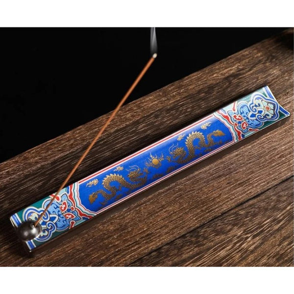 Enamel ceramic incense burner with blue dragon design. A sample piece of incense is burning at an angle.