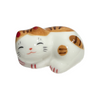 Ceramic cat-shaped object with white body and brown and black pattern on a white background.