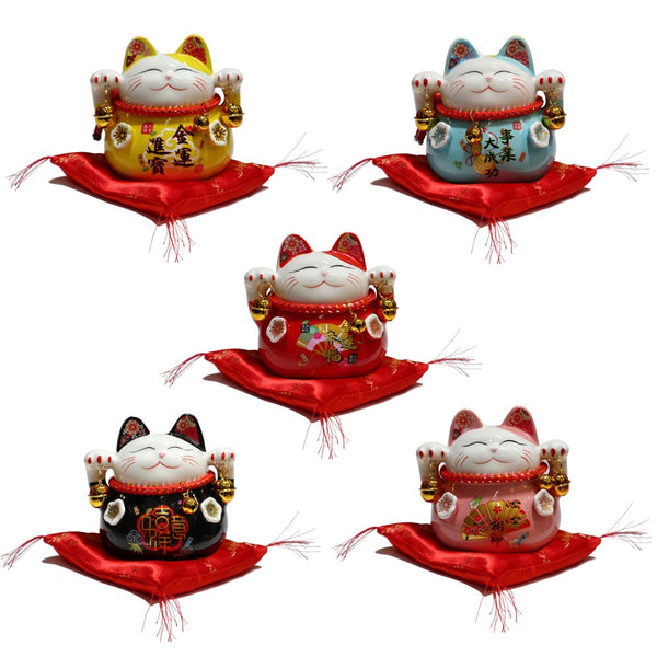 Lucky Cat Coin Banks in yellow, blue, red, black, and pink on a red cushion with golden plum blossom design.