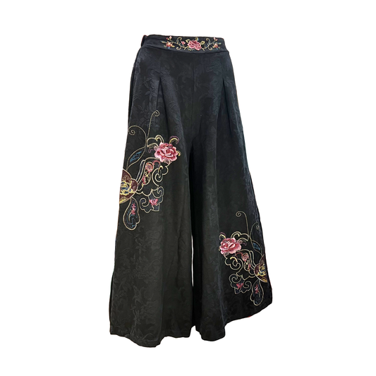 Black wide-leg trousers with pink and gold floral embroidery on the front, shown against a plain white background.