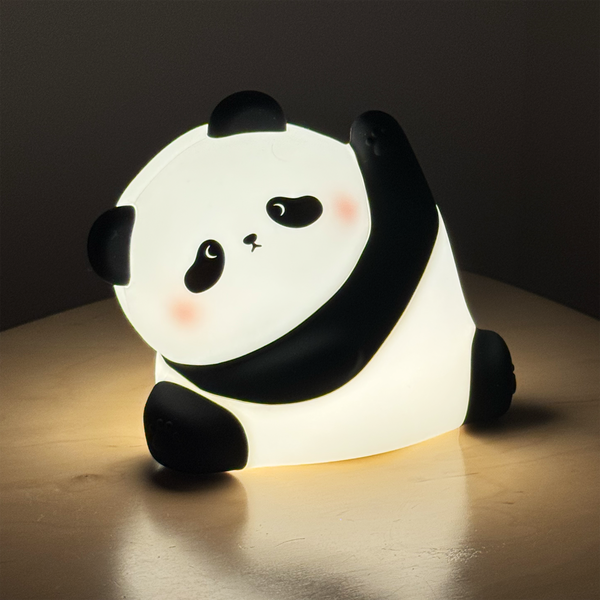 A cute panda-shaped night light glowing with warm white light, sitting on a wooden surface against a dark background.