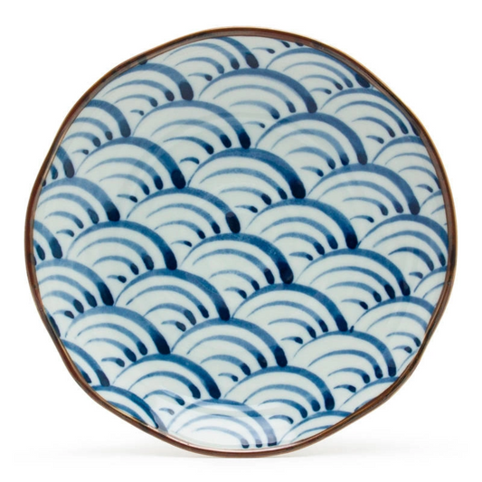 Round ceramic plate with scalloped edges, featuring blue and white wave patterns reminiscent of traditional Japanese design. Calm and elegant tone.