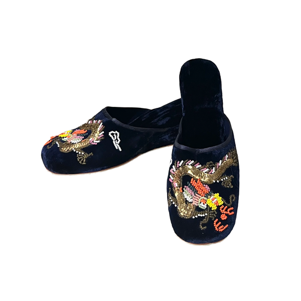 A pair of dark navy blue velvet slip-on slippers featuring detailed dragon embroidery with gold, red, and white sequins on the top, shown against a plain white background.