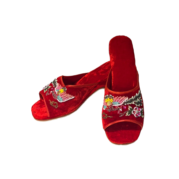 A pair of red velvet open-toe mule sandals decorated with colorful floral and bird embroidery and sequins, shown on a plain white background.