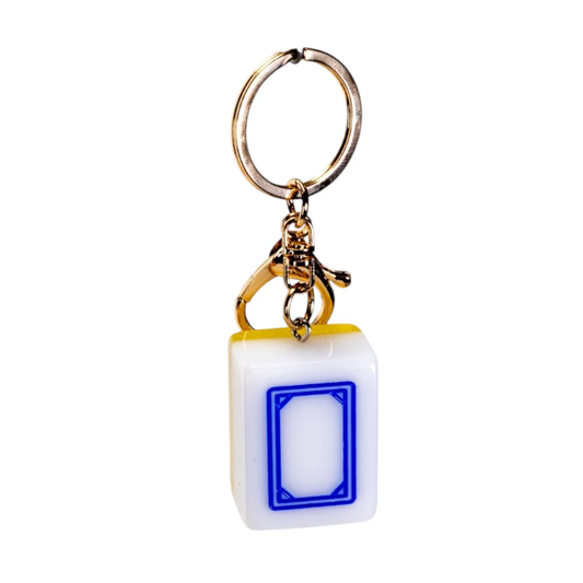 A novelty keychain shaped like a white mahjong tile with a blue door, attached to a gold-tone split ring and clasp, shown on a plain white background.