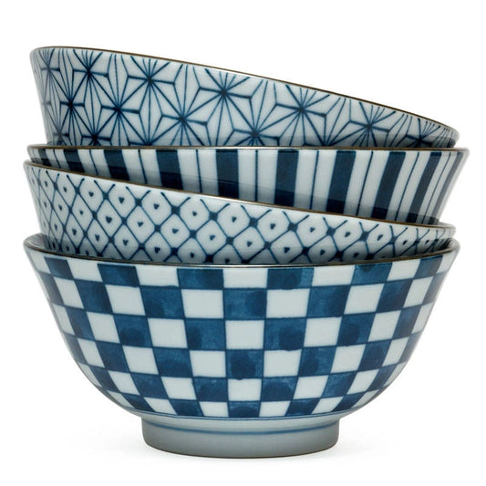 A stack of four blue and white ceramic bowls, each with a unique geometric pattern: starburst, stripes, hexagons, and checkerboard. The mood is elegant and refined.