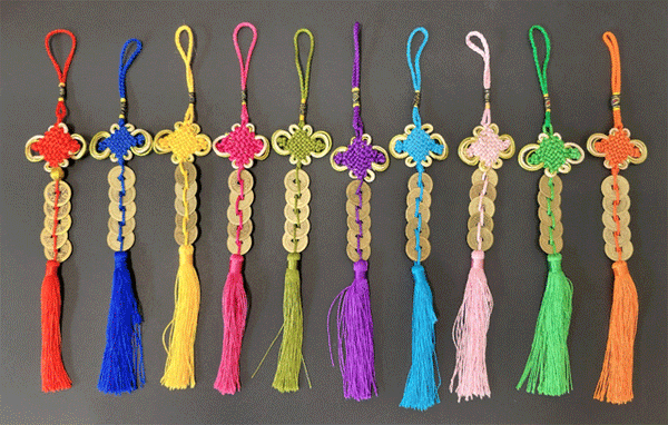 Five coin ornaments with tassels. Each ornament comes in a different color. From left to right, the colors go: Red, cobalt blue, yellow, fuchsia, sage green, purple, sky blue, pink, lime green, orange.. all of the ornaments hold five coins.