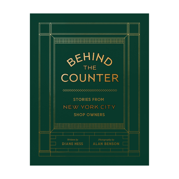 Book cover for 'Behind the Counter: Stories from New York City Shop Owners' with gold text and geometric border lines on a dark green background.