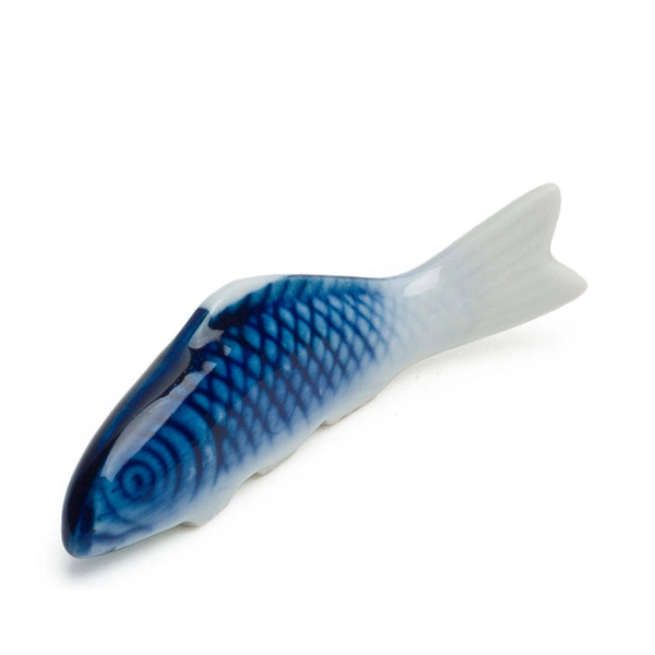 Blue and white ceramic fish-shaped chopstick rest on a white background