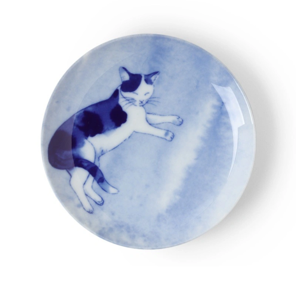 Round ceramic plate with a blue and white cat design on a light blue background