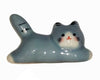 Ceramic cat-shaped object with gray, white, and black colors on a white background.