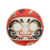 Red Daruma doll tea canister with black and white face design on a white background