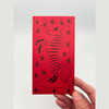 Red envelope with black horse design held by a hand on a light gray background