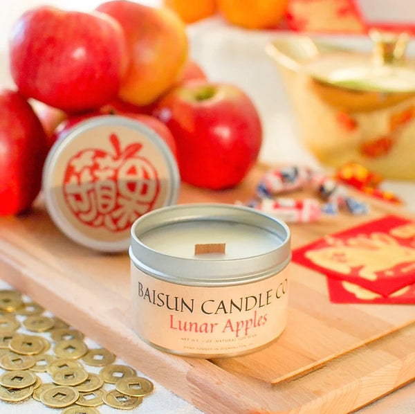 The Baisun lunar apple scented candle on a cutting board alongside fresh apples 