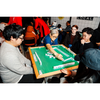 Group of people playing mahjong in an indoor setting.
