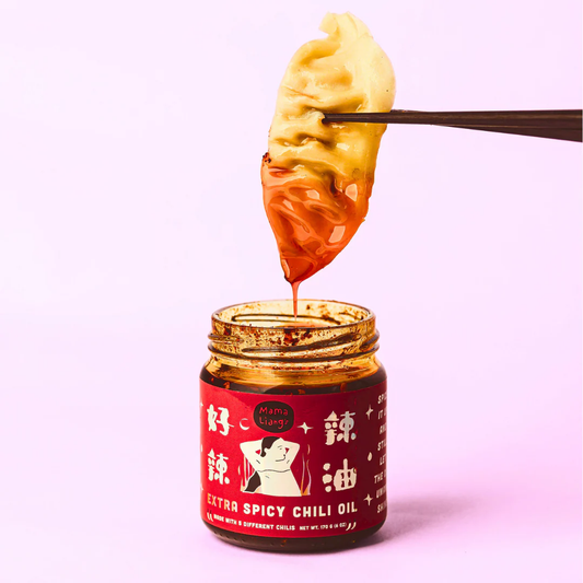 Jar of extra spicy chili oil with a spoonful being lifted, on a light pink background