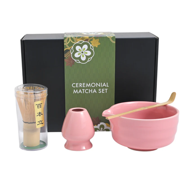 Ceremonial matcha set with pink bowl, whisk, and holder in front of a green box labeled 'Ceremonial Matcha Set'.