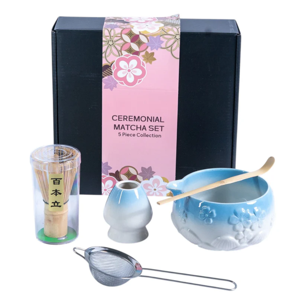 Ceremonial matcha set with blue bowl, whisk, and other tools in front of a decorative box.