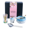 Ceremonial matcha set with blue bowl, whisk, and other tools in front of a decorative box.