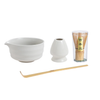 Set of Japanese tea-making tools including a white bowl, whisk, scoop, and glass container with wooden spoon on a white background.