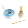 Tea-making set with blue ceramic bowl, whisk, and spoon on a white background