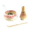 Tea-making set with ceramic bowl, whisk, and spoon on a white background