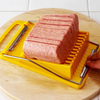 Yellow meat slicer with sliced meat on a wooden cutting board