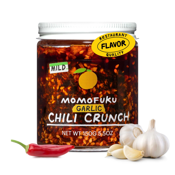 Jar of Momofuku Garlic Chili Crunch with garlic and a red chili pepper on a white background