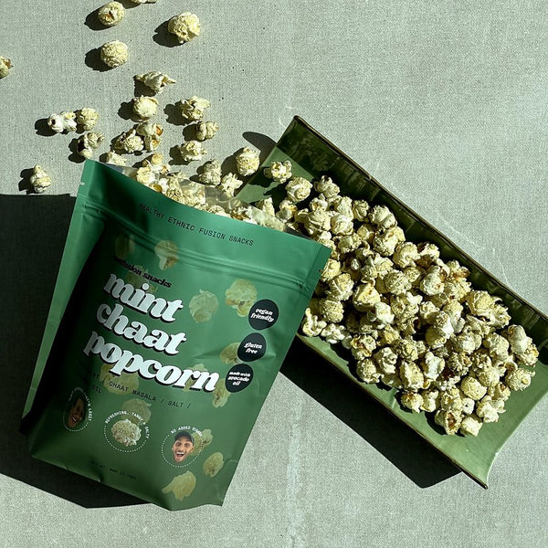 Green bag of mint chaat pop corn with green tray of popcorn