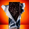 Open bar of chili crunch chocolate with silver wrapper on orange and yellow background