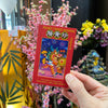 Pocket Chinese Almanac held by person with flowers in background