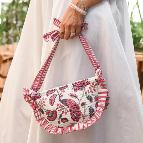 Person holding pink and white purse with peacock design